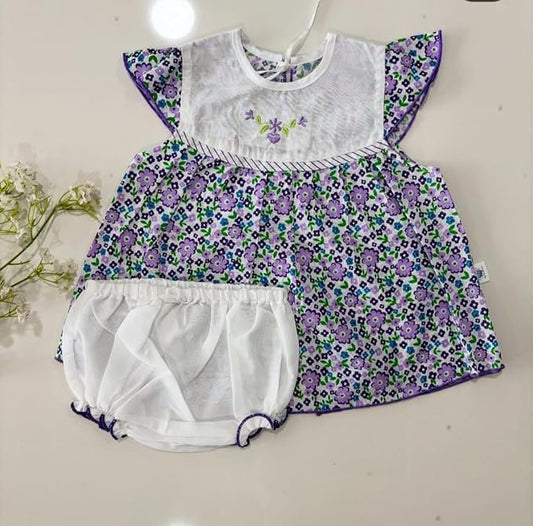Baby dress with purple floral pattern and white diaper on a light background
