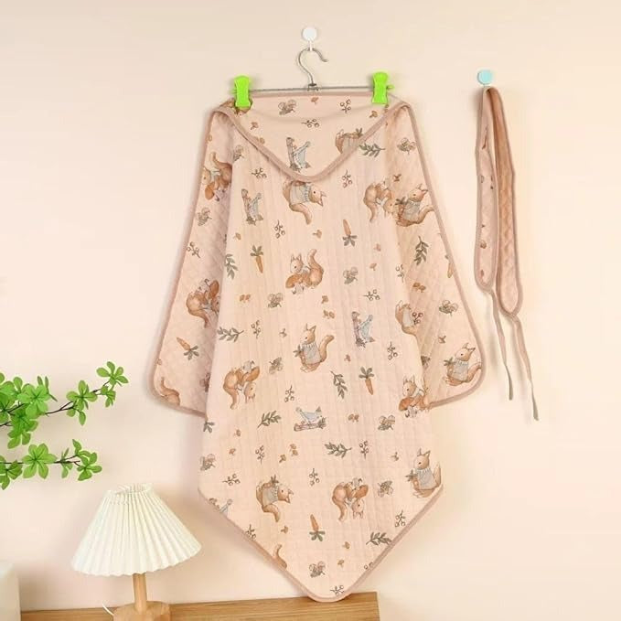 Baby blanket with animal pattern hanging on a hook against a light wall.