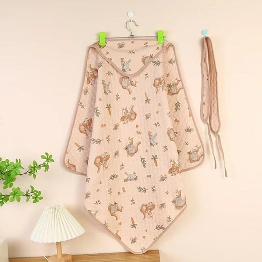 Baby blanket with animal pattern hanging on a hook against a light wall.