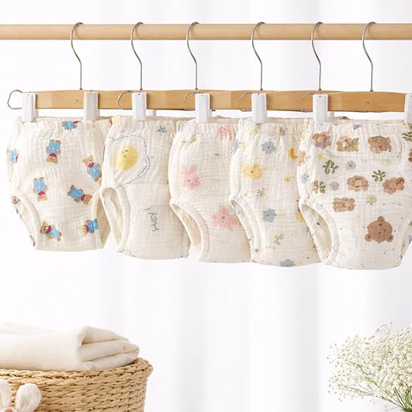 Baby diapers with cartoon designs hanging on a rack against a white curtain background.