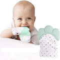 Baby holding a green teething toy with polka dots on a white background