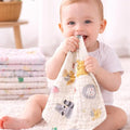Baby holding a soft toy with animal prints in a bright room.