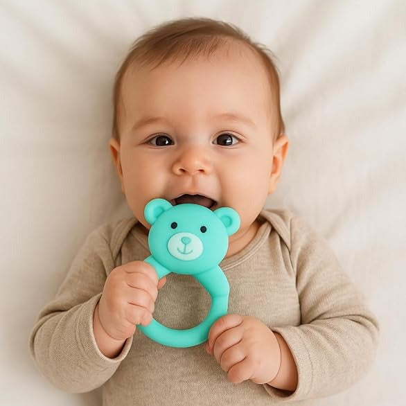 Baby holding a teal bear-shaped teether against a neutral background