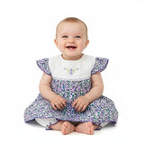 Baby wearing a floral dress with ruffled sleeves on a white background