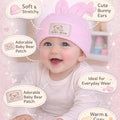 Baby wearing a pink baby hat with bunny ears and text highlighting features on a pink background.