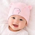 Baby wearing a pink bear hat on a white background