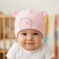 Baby wearing a pink hat with bear ears in a nursery setting