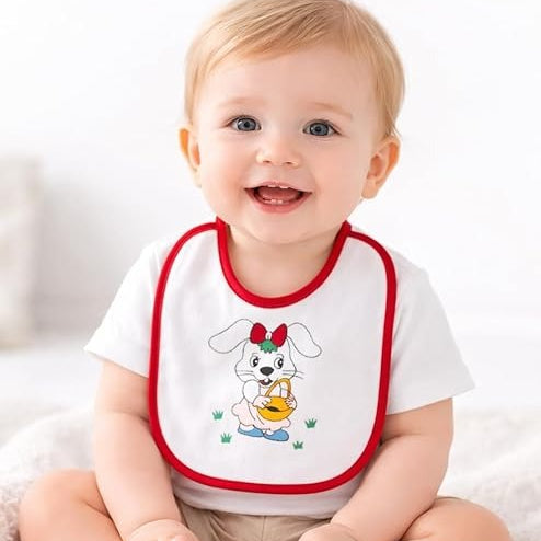 Baby wearing a white shirt with a cartoon dog design and red trim, sitting on a white blanket.