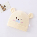 Beige baby hat with bear face design on a white background