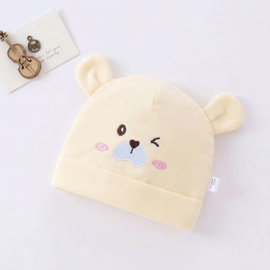 Beige baby hat with bear face design on a white background