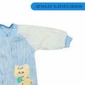 Blue baby outfit with white sleeves and a cartoon character patch on a white background
