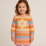 Child wearing a colorful striped dress with a flower design on a plain background