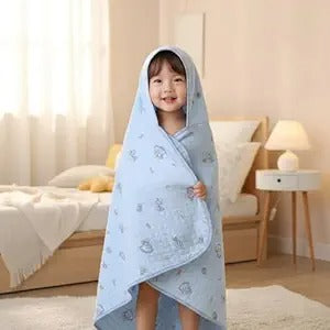 Child wrapped in a blue hooded towel in a bedroom setting