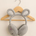 Gray bunny-shaped earmuffs on a wooden hanger against a beige background