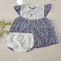 Baby dress with purple floral pattern and white diaper on a light background