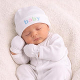 Newborn baby in a white outfit and hat with 'baby' text, lying on a soft surface.