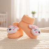 Pair of baby socks with cartoon face design on a soft surface