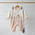 Baby romper with bunny design hanging on a wooden rod against a light wooden panel background