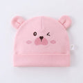 Pink baby hat with bear ears and face on a light gray background