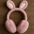 Pink bunny ear muffs on a wooden surface