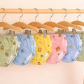 Set of colorful baby diapers on hangers against a beige background