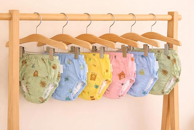 Set of colorful baby diapers on hangers against a beige background