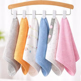 Set of colorful baby towels hanging on a wooden hanger against a white background