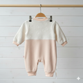 Baby romper with white top and beige bottom on a hanger against a light wooden background