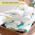 Stack of ultra soft muslin hankies with cartoon prints in a wooden box, labeled 'Ultra Soft Muslin Hanky'.