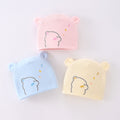 Three colorful baby hats with bear designs on a light background