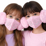 Two children wearing pink face masks with pom-pom attachments on a white background