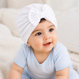Baby wearing a white turban and blue striped shirt on a soft beige background